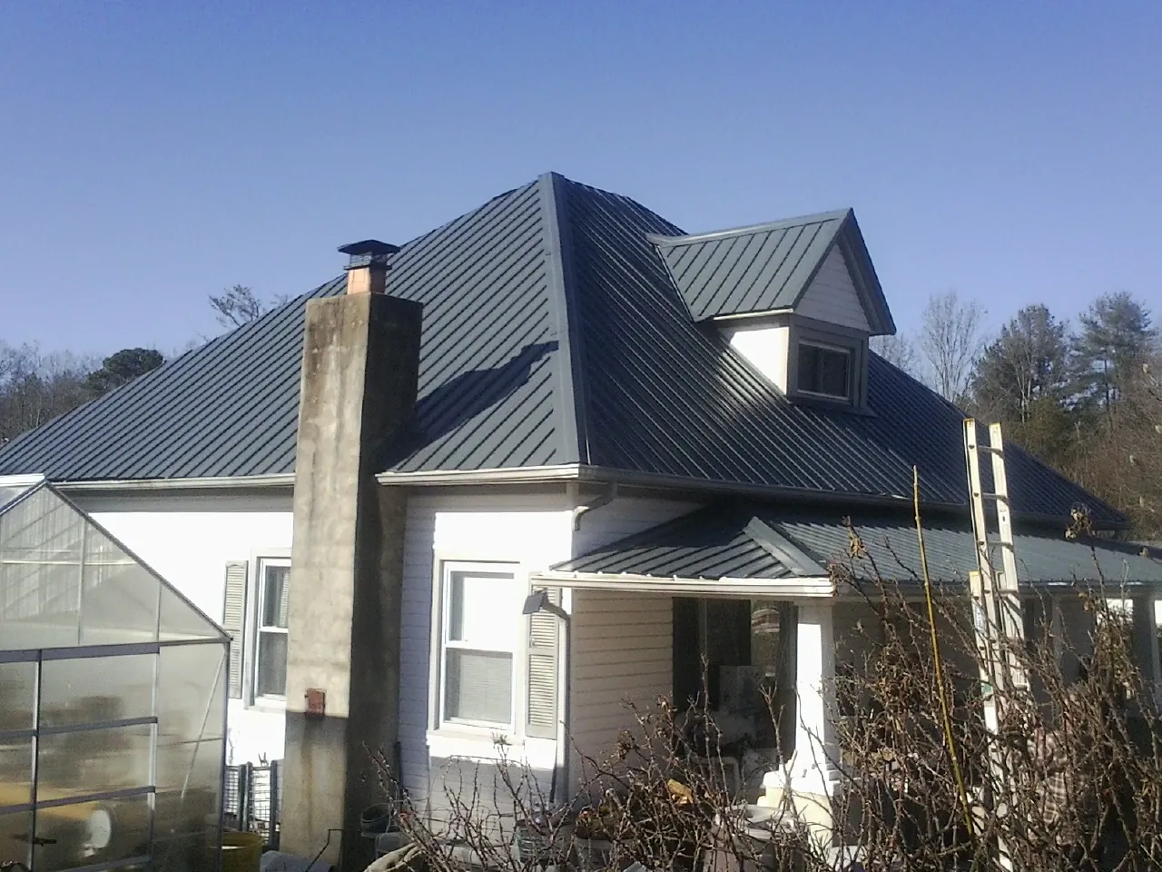 Dark blue standing seam metal roof on a white farmhouse with dormer — Slate & Tile Roof Repair by Roofing Brothers in Merrillville