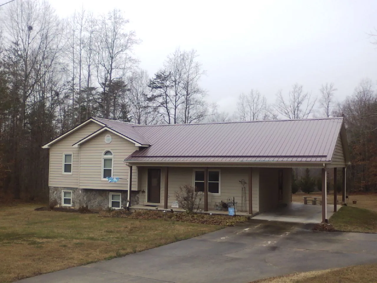Burgundy metal roof on a tan split level home with an attached carport in Merrillville