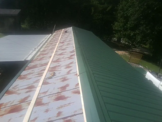 Old rusted panels beside newly installed green metal roofing — Wind Damage Roof Repair by Roofing Brothers in Merrillville