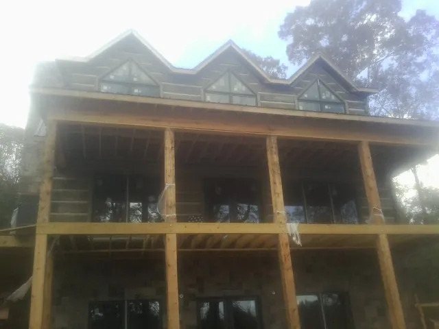 Dormers and porch framing on a large log home under construction — Roof Coating work by our crew in Merrillville