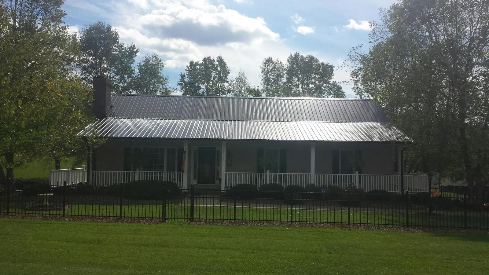 Gray metal roof on a brick ranch with a full width front porch — Gutter Guard Installation work by our crew in Merrillville