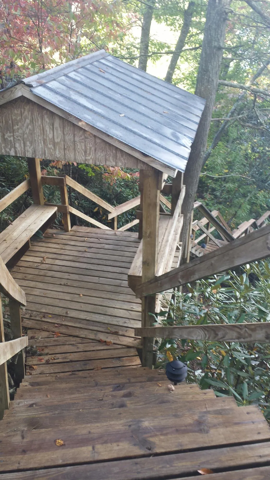 Metal roofed shelter over wooden steps on a wooded walkway — Skylight Repair & Installation work by our crew in Merrillville