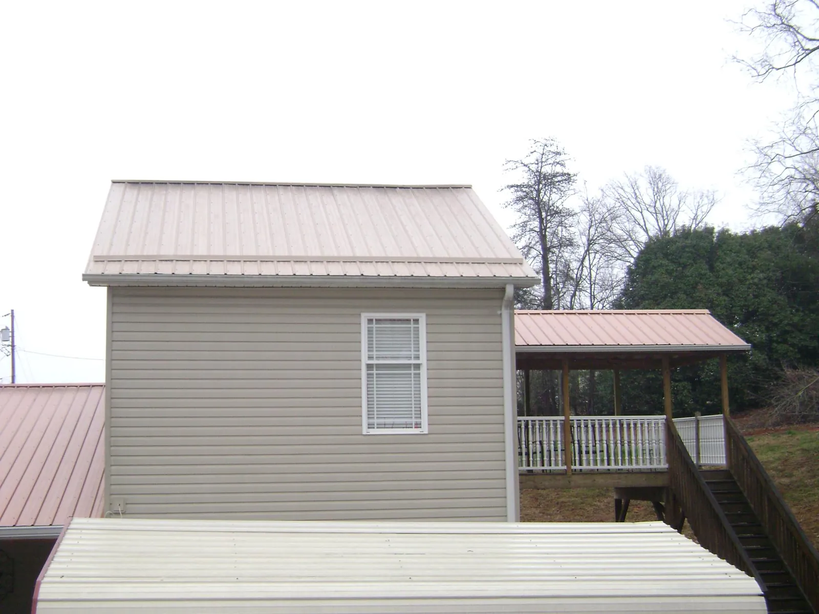 Tan metal roofs on a two story addition and attached porch, from a Roof Replacement job in Merrillville