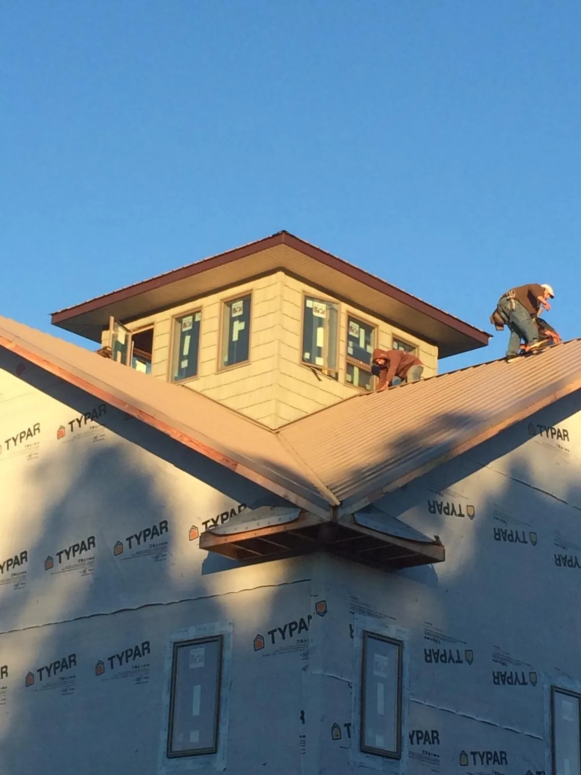 Roofers working around a rooftop cupola on a new metal roof at sunset — Roof Waterproofing in Merrillville by Roofing Brothers